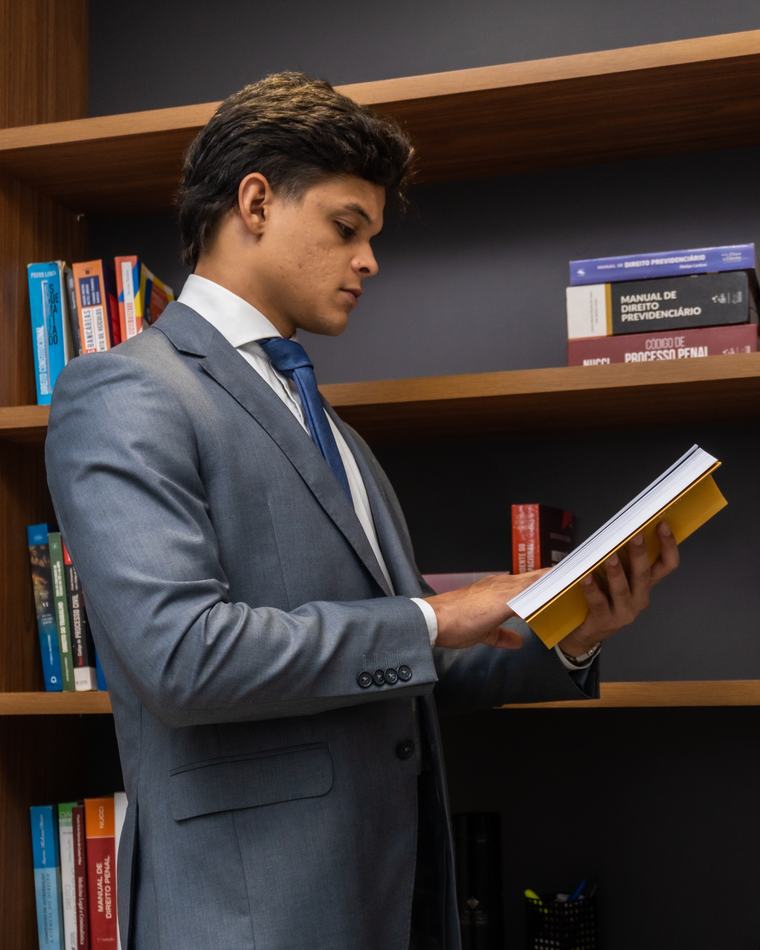 Dr. Khayo consultando um livro de Direito Previdenciário na estante do escritório